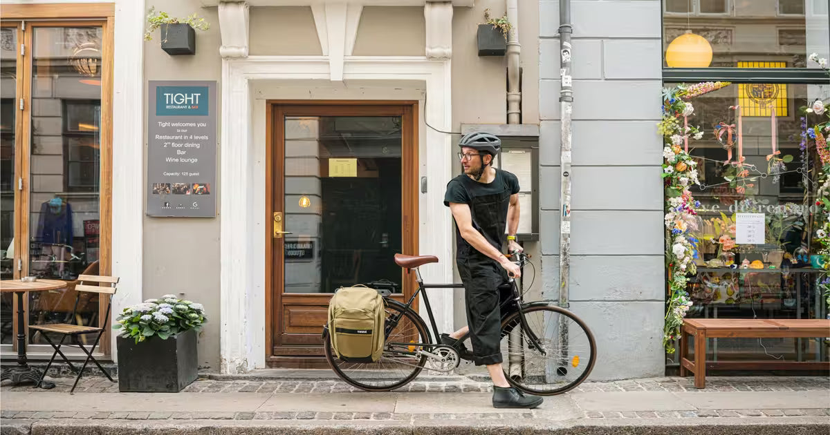 Ein Herr auf einem Fahrrad in einer Gasse in Kopenhagen - man sieht die Thule Fahrradtaschen montiert an seinem City Bike