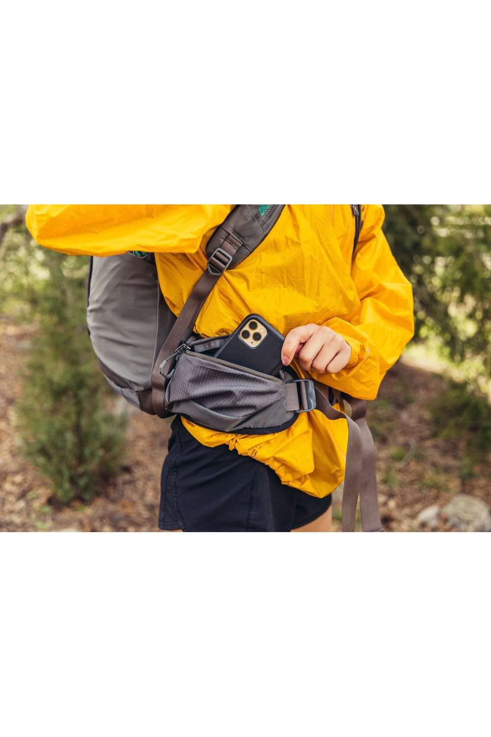 Der Gregory Jade Damenrucksack in einer Detailansicht - hier sieht man wie eine Dame ihr Handy in die Seitentasche des Rucksacks verstaut
